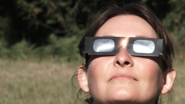 Model released woman wearing protective glasses reacts while watching a solar eclipse.
