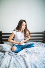 Young beauty woman suffering from abdominal pain while sitting on bed at home