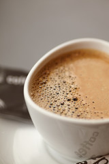 Close up ceramic cup of coffee on the table with coffee foam