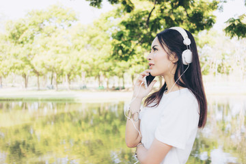 Beautiful young woman relaxing with smartphone and headphone listening to the music traveling