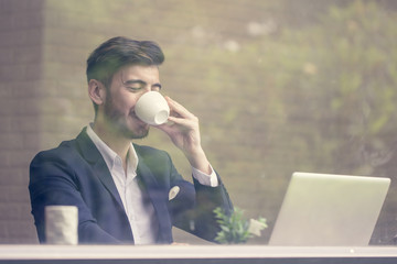 Businessman drinking Coffee while using Laptop with attractive smiling. Businessman working concept. vintage tone.