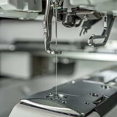 embroidery machines image close up at emboriding area parts as follows : needle, presser foot, laser guide, automatic threading, white thread,