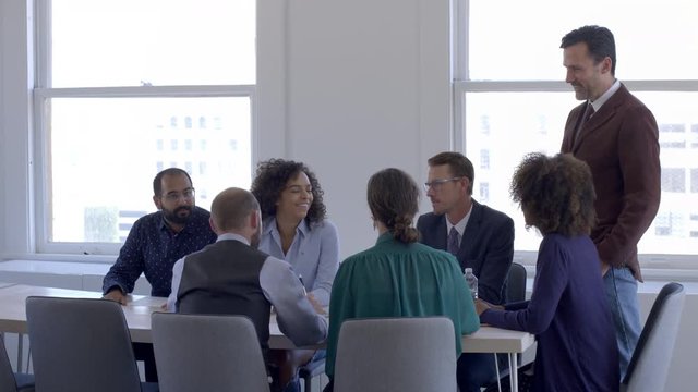 Mixed race team members in staff or board meeting, smile, laugh and nod in agreement during a meeting in a bright, day interior, urban office. 4K.
