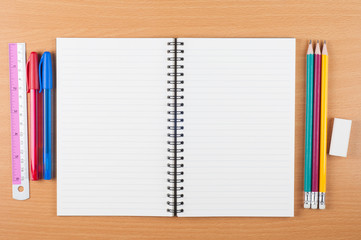 blank open spiral notebook with stationery on wooden desk, top view