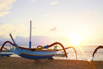 Traditional Balinese ships Jukung in Sanur beach at sunrise, Bali, Indonesia with beautiful morning sunlight