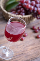 Glass of wine or grape juice and fruit on wooden table