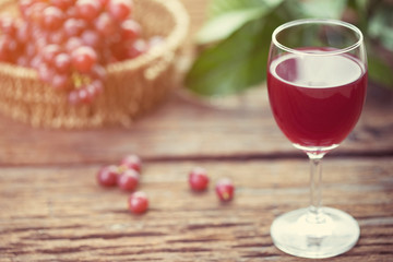Glass of wine or grape juice and fruit on wooden table