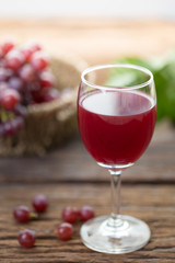 Glass of wine or grape juice and fruit on wooden table