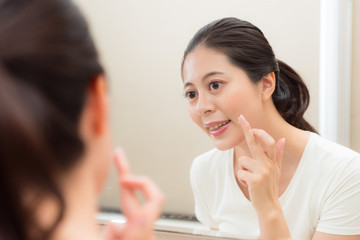 Obraz na płótnie Canvas smiling young woman applying face cream on finger