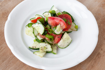 Salad of red tomatoes and cucumbers on a white plate
