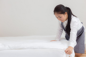 Obraz na płótnie Canvas Beautiful asian maid cleaning blanket in bedroom