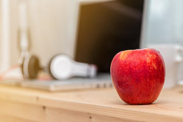 red Apple on wooden table with laptop background