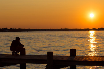 Naklejka na ściany i meble Man crabbing fishing during sunset on the boardwalk