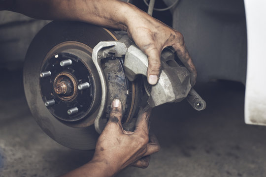 Hands of mechanic changing car braker in auto repair service.