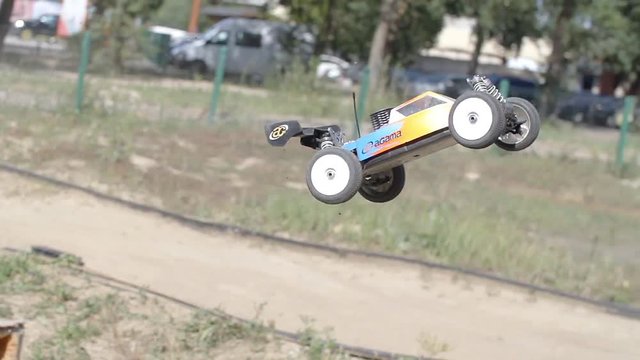 Radio controlled racing car riding on toy park 4k slow-motion video. R/C electric model flies up from springboard on race road