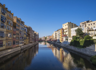Fototapeta na wymiar Girona river houses landmark, reflecting water in this famous city close to Barcelona on a blue summer sunny sky