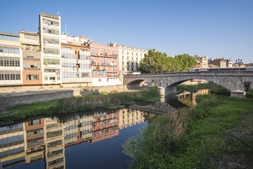 Fototapeta na wymiar Girona river houses landmark, reflecting water in this famous city close to Barcelona on a blue summer sunny sky