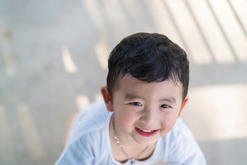 Little Asian kid playing and smiling at the playground under the sunlight in summer, shallow DOF