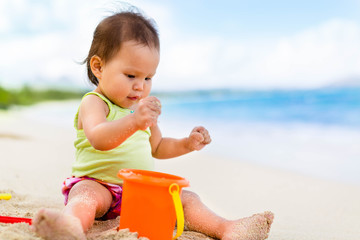 Two year old toddler playing with her toys on the beach
