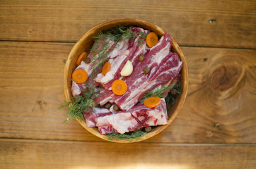 Pork meat with vegetables. Raw pork ribs prepared for cooking. Carrot and garlic with fat in  Clay bowl