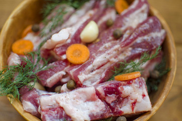 Pork meat with vegetables. Raw pork ribs prepared for cooking. Carrot and garlic with fat in  Clay bowl