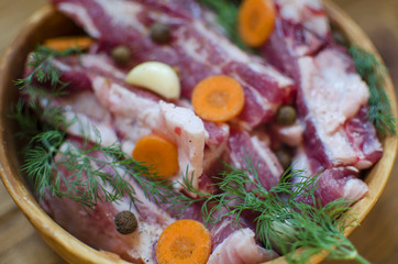 Pork meat with vegetables. Raw pork ribs prepared for cooking. Carrot and garlic with fat in  Clay bowl