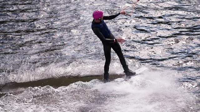 Wakeboarder rides at cable wake park HD wakeboarding slow-motion video. Water extreme sport. Man holds rope handle