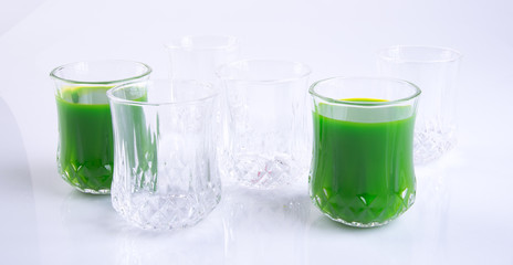 juices or fresh green smoothie in glasses on background.