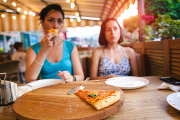 Two girls are eating pizza.