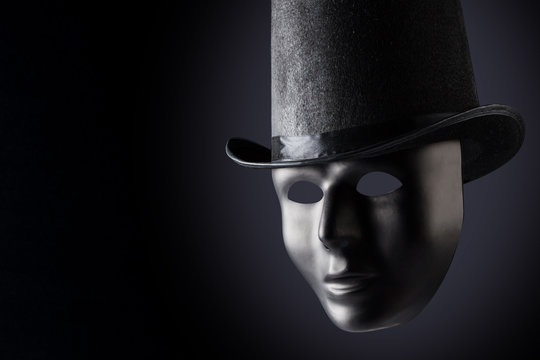 Black Mask Face Closeup Wearing Black Top Hat On Black Background With Copy Space. Social Masking And Mystery Concept