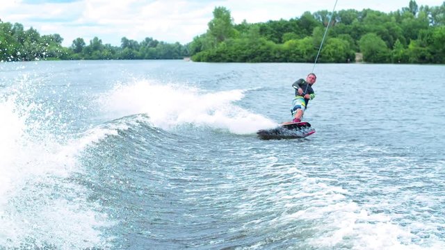Wakeboarder rides behind boat HD wakeboarding slow-motion pov video. Man surfs on waves. Water extreme sport.