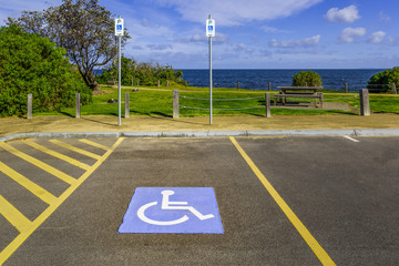 Disabled parking spot and signs in a park near ocean beach