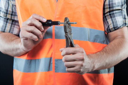 Close-up worker holding tools making obscene gesture