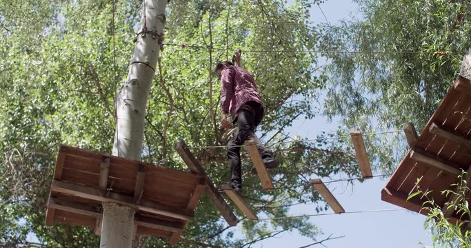 Male teenager moving on adventure rope park 4k video. Young climber running on rope ladder for extreme adventure