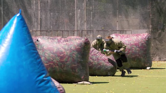 Paintball players aiming and shooting HD game slow-motion video. Man team with gun hitting on playing field venue. Sport action war battle fighting