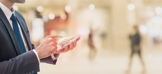 Businessman using smartphone in shopping mall space background and copy space.