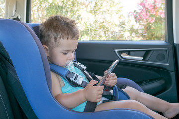toddler boy playing smartphone in the car