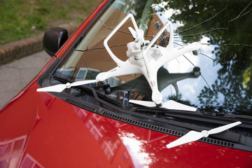 Damaged white drone on broken car windshield