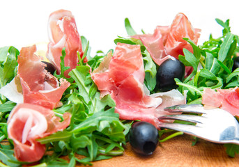 chopping board with aragula and raw ham
