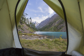 In the forest the tourist lies in a tent. Around the mountain, forest and lake.