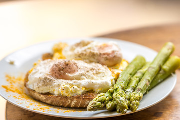 Turmeric on poached eggs on sourdough bread with asparagus tips
