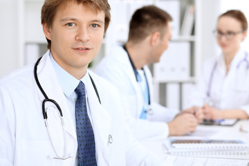 Cheerful smiling male doctor with medical staff at the hospital