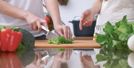 Close-up of four human hands are cooking in a kitchen. Friends having fun while preparing fresh...