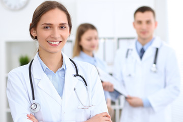 Young beautiful female doctor smiling  on the background with patient  in hospital