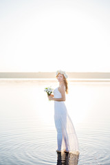 Fototapeta na wymiar Charming and happy girl florist in white dress and with white flowers on the lake