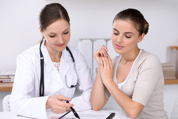 Doctor and  patient  sitting at the desk. The physician or therapist makes a diagnosis. Health care, medicine and patient service concept