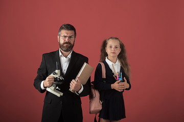Kid and tutor hold microscope, book and stationery