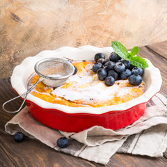 Delicious homemade gluten free cheesecake made from cottage cheese, decorated with blueberries and mint on wooden background. Healthy food concept with copy space.