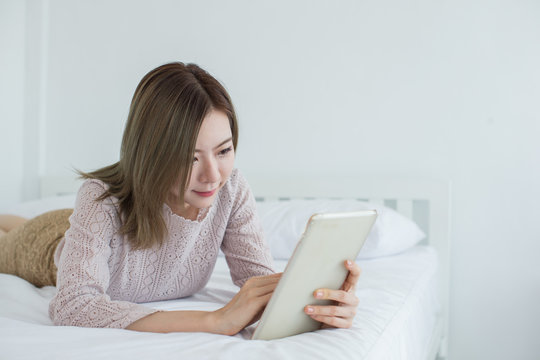 Young Asian business woman using digital tablet in bedroom with copy space