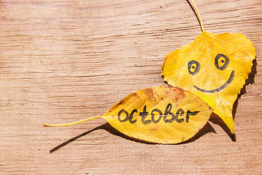 Yellow leaves with the image of a happy face and the inscription Octobe